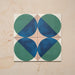 Group image showing four Geometry Ocean 20x20cm geometric patterned tiles arranged to create a circular motif, featuring blue and green semicircles with sand and white corners, photographed against a neutral stone background.