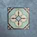 Four Europa Gothenberg 20x20cm Victorian Moroccan style tiles displayed together against a textured blue background, forming a symmetrical geometric pattern in blue, mint green and cream tones.