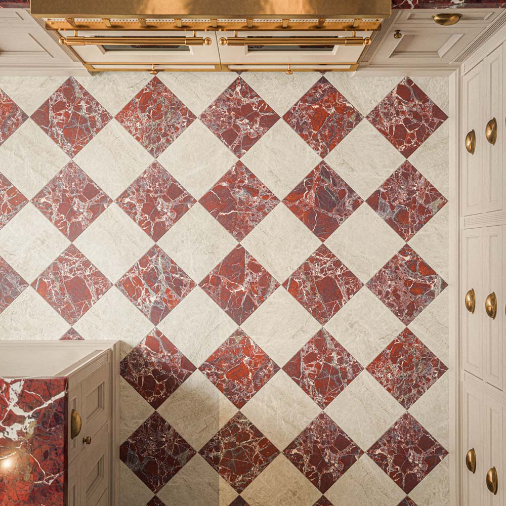Overhead view of a kitchen featuring Grand Bazaar Mahal Matt 30x30cm marble-effect chequerboard floor tiles, with warm ivory and rich burgundy squares arranged in a diagonal pattern, showcasing subtle stone-effect textures and contrasting marble-effect veining, paired with cream cabinetry, brass handles and burgundy marble-effect worktops.