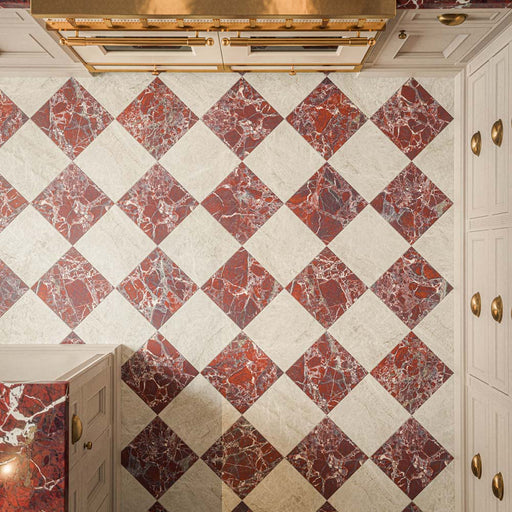 Overhead view of a kitchen featuring Grand Bazaar Mahal Matt 30x30cm marble-effect chequerboard floor tiles, with warm ivory and rich burgundy squares arranged in a diagonal pattern, showcasing subtle stone-effect textures and contrasting marble-effect veining, paired with cream cabinetry, brass handles and burgundy marble-effect worktops.