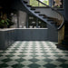 Interior featuring Grand Bazaar Verde Green and Grand Bazaar Mahal marble-effect chequerboard floor tiles, combining rich green tones with soft white marble-effect tiles to create a timeless checkerboard design. Styled with dark blue cabinetry, brass accents, marble worktops and a sweeping staircase, creating a sophisticated and luxurious interior with classic character and contemporary elegance.