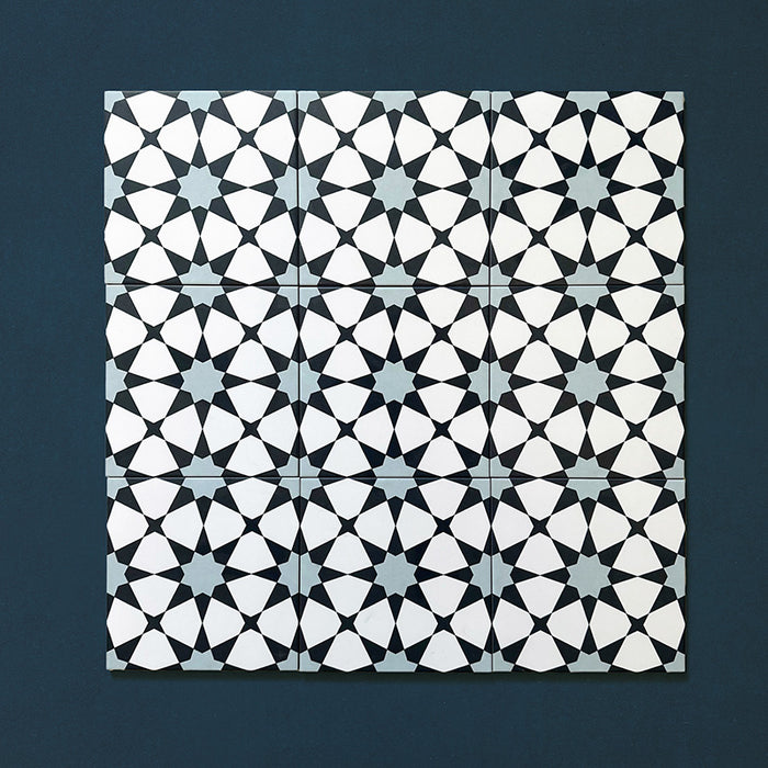 Close-up of multiple Agraba Azul Blue 20x20cm Moroccan-style ceramic tiles arranged in a grid, displaying a geometric star pattern in navy, light blue, and white on a deep blue background.