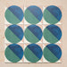 Group image showing nine Geometry Ocean 20x20cm geometric patterned tiles arranged in a grid, featuring blue and green semicircles on a sand and white background, photographed against a neutral stone surface.
