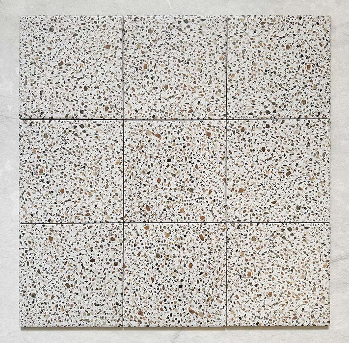 Flatlay featuring a group of Dino Terrazzo Blanco Dots 20x20cm terrazzo-style ceramic tiles, displaying a uniform white base with multicoloured stone flecks across nine tiles.