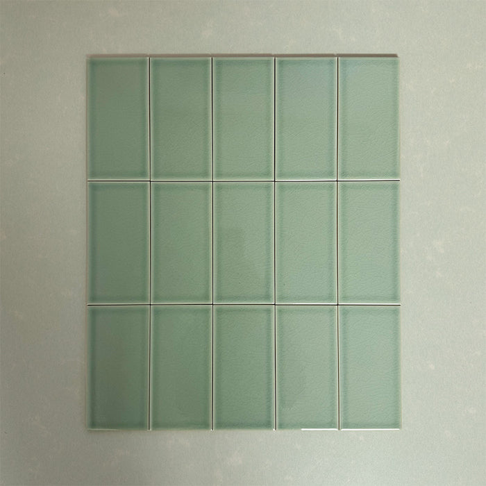 Flat lay of Finchley Lime Green 7.5 × 15cm ceramic tiles with a crackle glaze finish, highlighting soft green tones, subtle surface texture and gentle tonal variation for elegant wall tile designs.