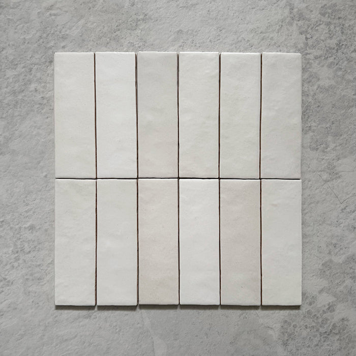 Zellij Chalk White Brick Moroccan-style tiles in a 6.5cm x 20cm brick format, arranged as a grouped layout to highlight the soft matt white finish and natural handmade surface variation on a neutral stone-effect background.