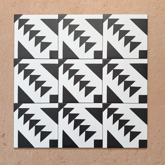 Alhambra Alkazar 20x20cm Moroccan tiles arranged in a group layout, showcasing a bold black and white geometric triangle pattern on a warm terracotta background.