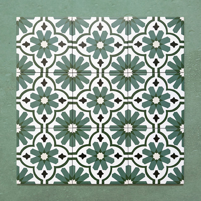 Flatlay featuring a group of Clarence House Verde Green 20x20cm Victorian Moroccan-style porcelain tiles, displaying a repeating geometric floral pattern in deep green, white, and black on a textured green background.