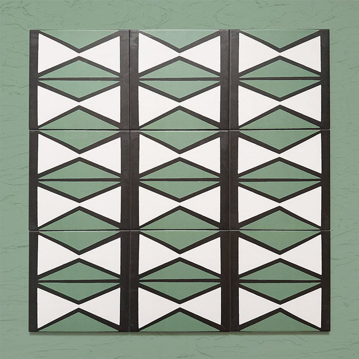 Group image showing multiple Geometry Hourglass 20x20cm patterned tiles arranged in a repeating vertical layout, featuring alternating green and cream hourglass shapes with bold charcoal outlines, photographed against a textured sage-green background.