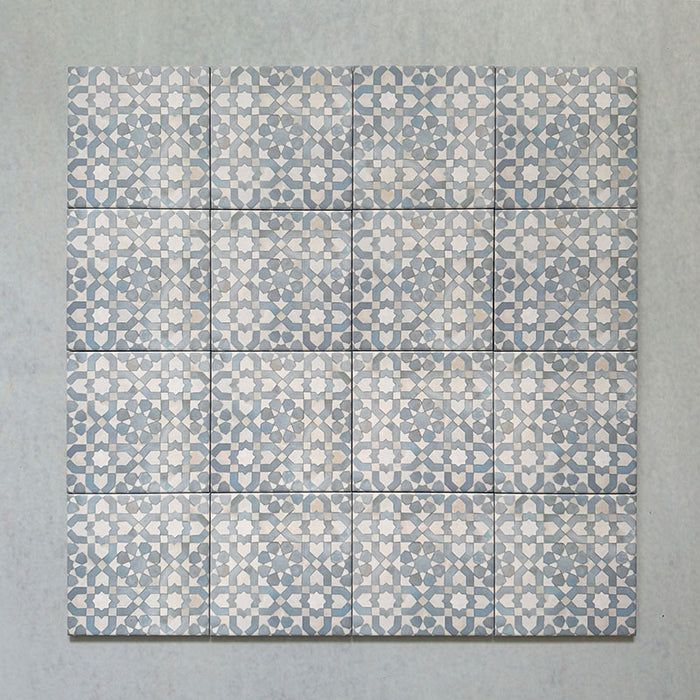 Group of Bedouin Tetuan Blue Moroccan-style ceramic tiles, 15x15cm each, arranged to show the repeating star and cross pattern in soft blue, cream, and taupe tones with a handcrafted finish on a pale surface background.