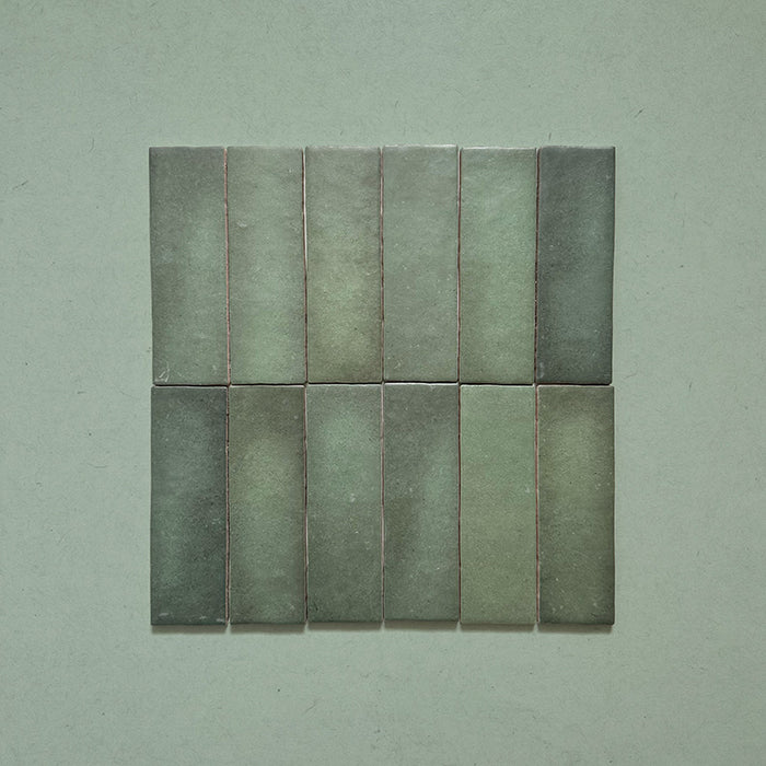 Zellij Malachite Green Brick Moroccan Style 6.5cm x 20cm group of tiles, slim rectangular brick format, rich malachite green tones with natural shade variation, glossy glazed finish, handcrafted Moroccan zellige style, tiles arranged together on a neutral background to show colour variation.