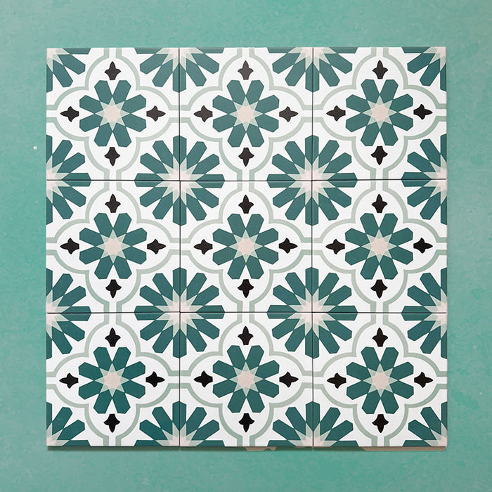 Flatlay featuring a group of Clarence House Teal Green 20x20cm Victorian Moroccan-style porcelain tiles, displaying a repeating geometric floral pattern in teal, white, and black on a green background.