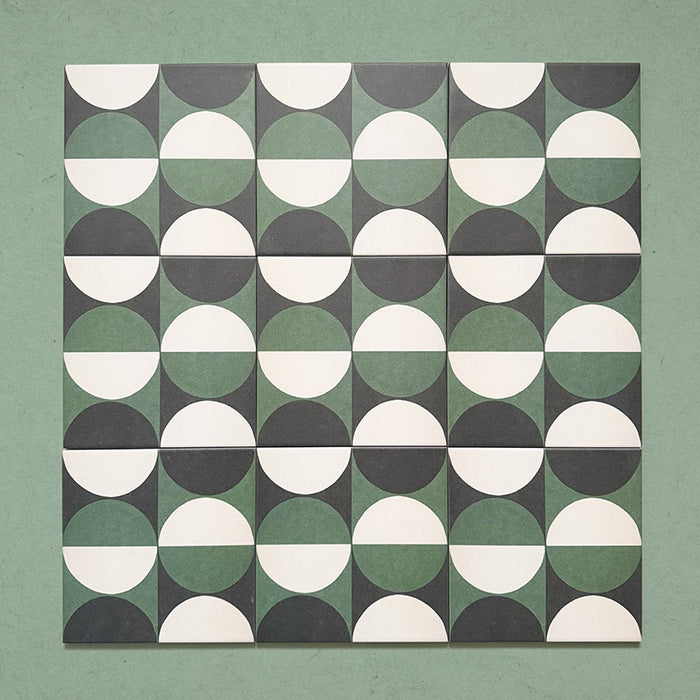 Group image showing multiple Geometry Circulo 20x20cm geometric patterned tiles arranged in a repeating layout, featuring green, black, and cream semicircle motifs, photographed against a soft green textured background.