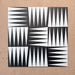Group of Alhambra Tavla 20x20cm Moroccan tiles displaying a striking black and white triangular geometric pattern, arranged to create a bold, dynamic layout on a warm textured background.