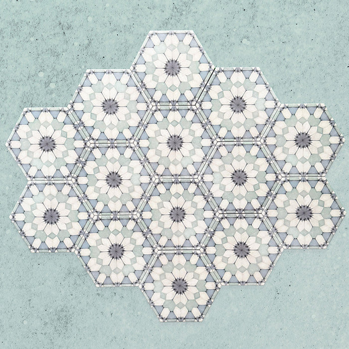Maroush Frost Blue 18.7x21.6cm Moroccan hexagonal tiles arranged in a group, showcasing a repeating starburst floral pattern in soft blue, white, and grey tones on a textured pale blue background.