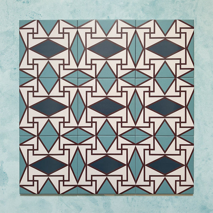 Group image showing multiple Geometry Iris 20x20cm patterned tiles arranged in a repeating layout, featuring an intricate geometric design in teal, navy, terracotta-red, and cream, photographed against a soft mottled aqua background.