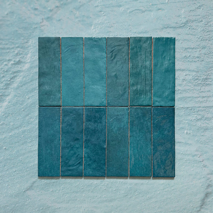 Zellij Peacock Green brick tiles, 6.5cm x 20cm, Moroccan style glazed ceramic wall tiles in deep peacock green tones with natural shade variation, glossy finish, and gently uneven handcrafted texture, shown as a grouped tile layout on a pale textured background.