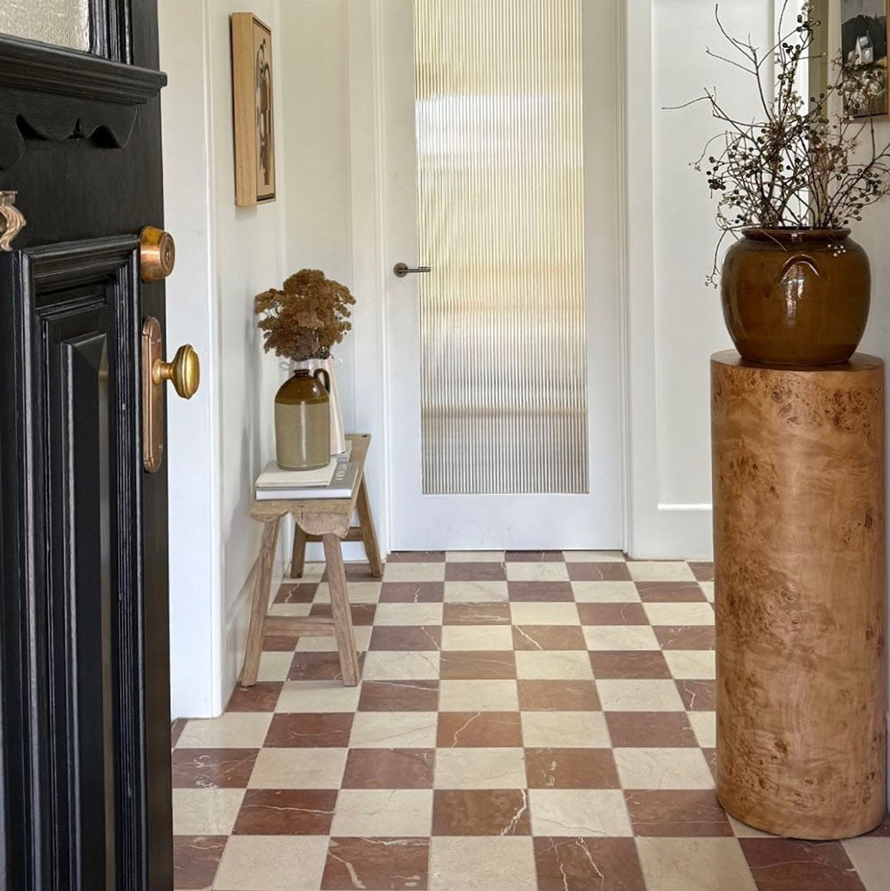 Hallway featuring Fitzrovia Rosso natural marble tiles in 15.2x15.2cm format with a tumbled finish, laid in a classic checkerboard pattern and styled with warm wood furniture and neutral walls.