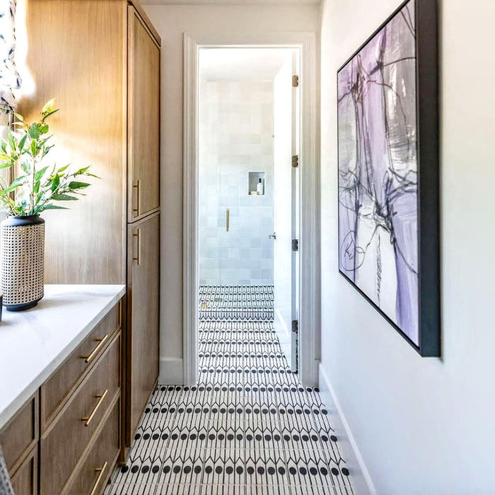 Alhambra Felisa 20x20cm Moroccan tiles laid in a hallway, featuring a bold black and white linear pattern that draws the eye through to a bright bathroom, complemented by wooden cabinetry and gold hardware for a contemporary Moroccan-inspired look.