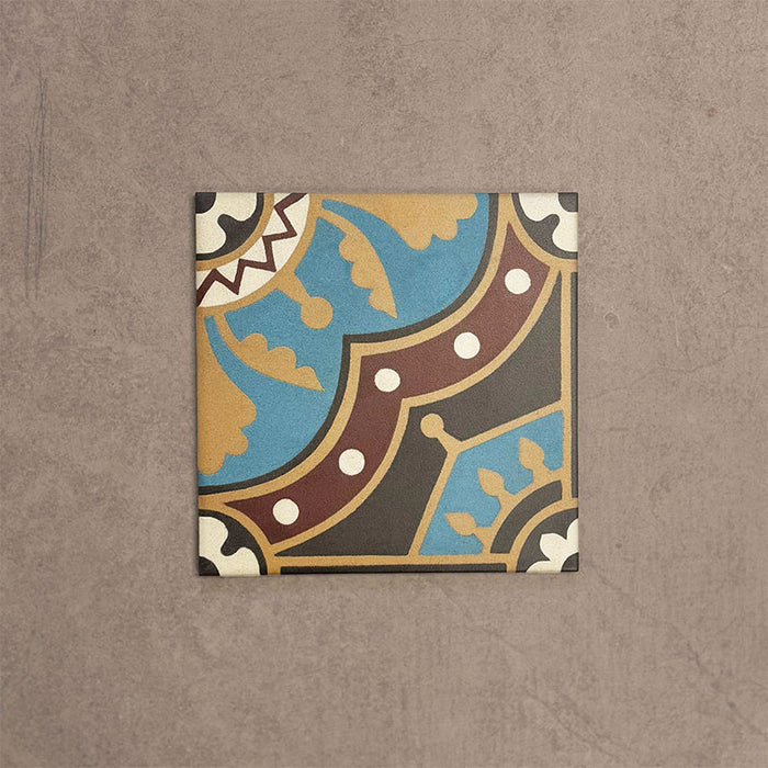 Single Europa Hanover 20x20cm Victorian Moroccan style tile displayed against a textured beige background, featuring a decorative geometric and floral pattern in blue, terracotta, mustard and cream tones in a close-up product setting.