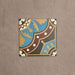 Single Europa Hanover 20x20cm Victorian Moroccan style tile displayed against a textured beige background, featuring a decorative geometric and floral pattern in blue, terracotta, mustard and cream tones in a close-up product setting.