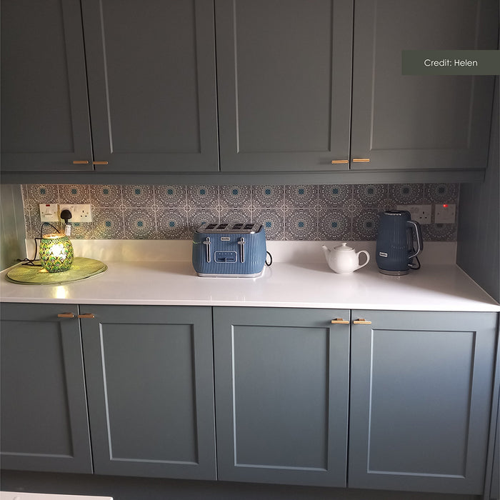 Kitchen splashback featuring Pasha Kashani Moroccan MINI tiles 15 × 15cm, with intricate geometric patterning in soft grey and blue tones. Paired with shaker cabinetry, brass handles, and a white worktop for a balanced, characterful finish.