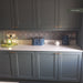 Kitchen splashback featuring Pasha Kashani Moroccan MINI tiles 15 × 15cm, with intricate geometric patterning in soft grey and blue tones. Paired with shaker cabinetry, brass handles, and a white worktop for a balanced, characterful finish.