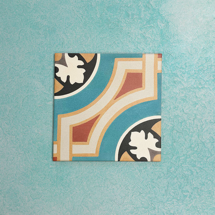 Single Europa Helsinki 20x20cm Victorian Moroccan style tile displayed against a textured aqua background, featuring a decorative geometric corner pattern in teal, terracotta, cream and black tones in a close-up product setting.