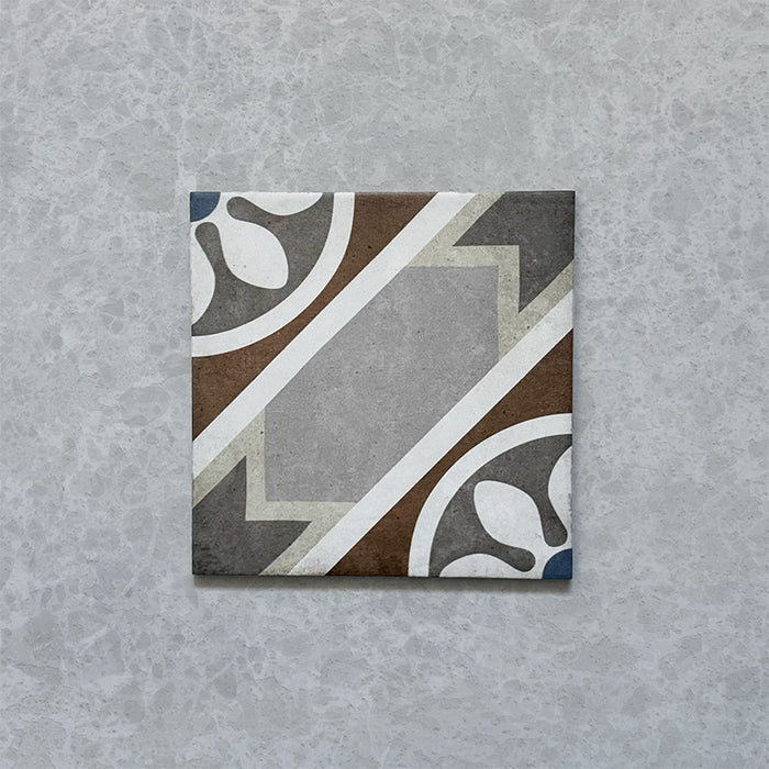 Single tile from the Carnaby Heythrop Victorian-style collection, 20x20cm porcelain wall and floor tile, featuring a geometric floral pattern in taupe, terracotta, grey, and blue on a softly aged background.