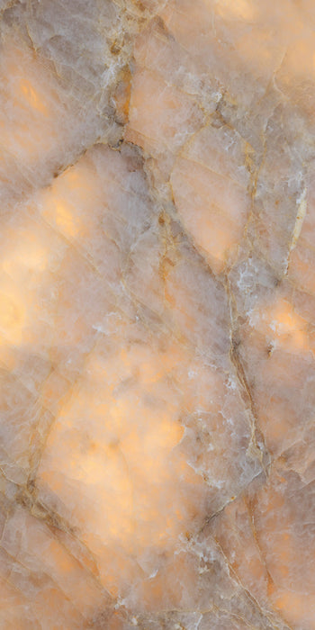Close-up of Illuminati Precious Stone Amber 60 × 120cm polished porcelain tiles, featuring warm amber, cream, and taupe gemstone-inspired tones with delicate veining, luminous detailing, and a high-gloss natural stone effect finish.