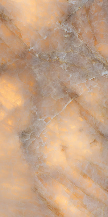 Close-up of Illuminati Precious Stone Amber 60 × 120cm polished porcelain tiles, featuring warm amber, cream, and taupe gemstone-inspired tones with delicate veining, luminous detailing, and a high-gloss natural stone effect finish.