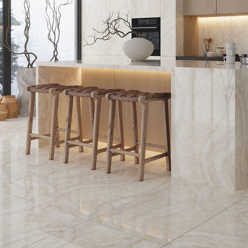 Contemporary kitchen featuring Illuminati Precious Stone Ivory 60 × 120cm polished porcelain floor and wall tiles, showcasing soft ivory and cream gemstone-inspired veining, paired with warm wood bar stools and minimalist cabinetry.