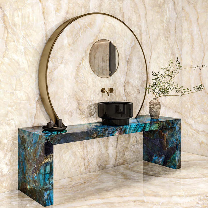 Luxury bathroom featuring Illuminati Precious Stone Ivory 60 × 120cm polished porcelain wall and floor tiles, showcasing soft ivory gemstone-inspired veining, paired with a statement mirror, black vessel basin, and bold blue stone-effect vanity unit.