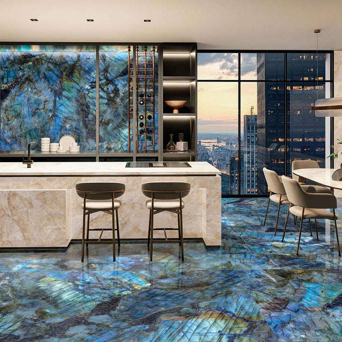Open-plan kitchen and dining area featuring Illuminati Precious Stone Labradorite 60 × 120cm polished porcelain floor tiles, showcasing vivid blue gemstone-inspired veining, paired with marble-effect cabinetry, dark shelving, and contemporary furnishings.
