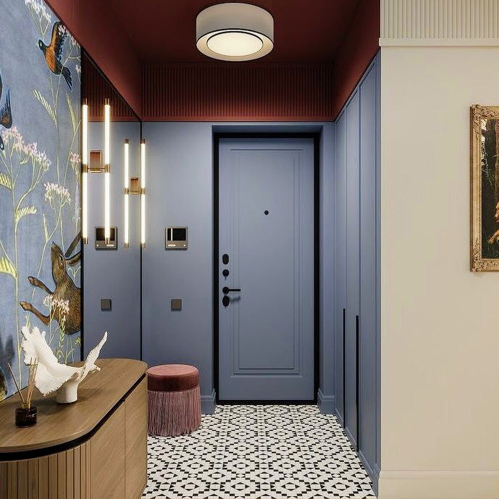 Hallway interior featuring Belgravia Black & White 28x28cm Victorian-style patterned floor tiles, styled with blue panelled walls, statement wallpaper, warm wood console, and soft lighting in a contemporary entrance space.