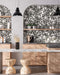 Kitchen setting featuring Noventa Terrazzo Nero 59x59cm matt porcelain wall and floor tiles, showcasing a bold terrazzo effect with contrasting white stone fragments set against a deep black base, installed within arched alcoves and paired with warm wood cabinetry and soft neutral surfaces for a refined, architectural finish.