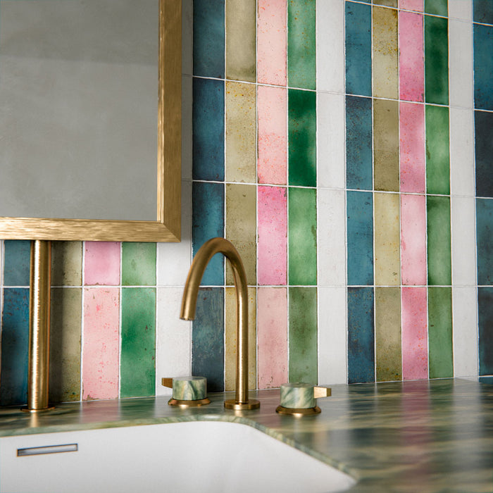 Bathroom setting featuring Fusion collection gloss brick tiles in a vertical striped layout, blending soft greens, pinks and neutrals, paired with a marble vanity and brass fittings for a vibrant, design-led finish.