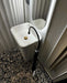 Bathroom setting featuring Noventa Terrazzo Nero 59x118cm matt porcelain wall and floor tiles, showcasing a bold terrazzo effect with contrasting white stone fragments set against a deep black base, installed across the floor and paired with sculptural sanitaryware, fluted wall panelling and matte black fittings for a refined, contemporary finish.