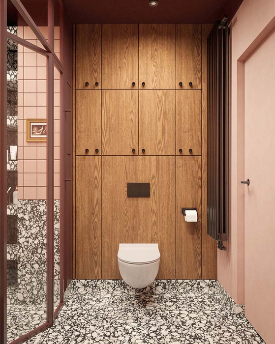 Bathroom setting featuring Noventa Terrazzo Nero 59x118cm matt porcelain wall and floor tiles, showcasing a bold terrazzo effect with contrasting white stone fragments set against a deep black base, used across both floor and lower wall sections, paired with soft blush wall tiles, warm wood cabinetry and tonal framing for a refined, design-led finish.