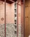 Bathroom setting featuring Noventa Terrazzo Nero 59x118cm matt porcelain wall and floor tiles, showcasing a bold terrazzo effect with contrasting white stone fragments set against a deep black base, used across both floor and lower wall sections, paired with soft blush wall tiles, warm wood cabinetry and tonal framing for a refined, design-led finish.