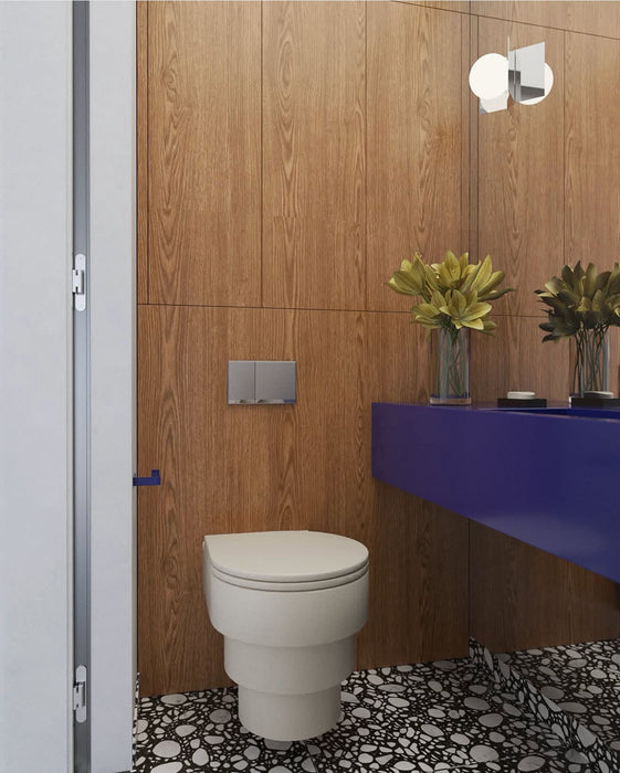 Bathroom setting featuring Noventa Terrazzo Nero 59x59cm matt porcelain wall and floor tiles, showcasing a bold terrazzo effect with crisp white stone fragments set against a deep black base, carried across both floor and stepped detailing, paired with warm wood panelling and a striking cobalt vanity for a contemporary, design-led finish.