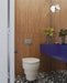 Bathroom setting featuring Noventa Terrazzo Nero 59x59cm matt porcelain wall and floor tiles, showcasing a bold terrazzo effect with crisp white stone fragments set against a deep black base, carried across both floor and stepped detailing, paired with warm wood panelling and a striking cobalt vanity for a contemporary, design-led finish.