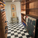 Wine cellar interior featuring Maison Plain Black Base and Maison Plain White Base 20x20cm Victorian-style floor tiles, installed in a classic chequerboard layout, styled with wooden wine racks, shelving, and decorative artwork.