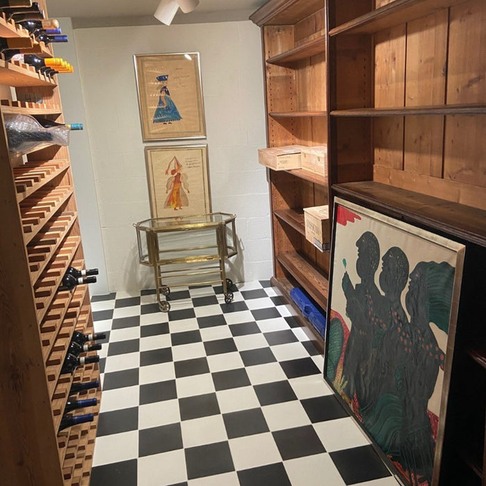 Wine cellar interior featuring Maison Plain Black Base and Maison Plain White Base 20x20cm Victorian-style floor tiles, installed in a classic chequerboard layout, styled with wooden wine racks, shelving, and decorative artwork.