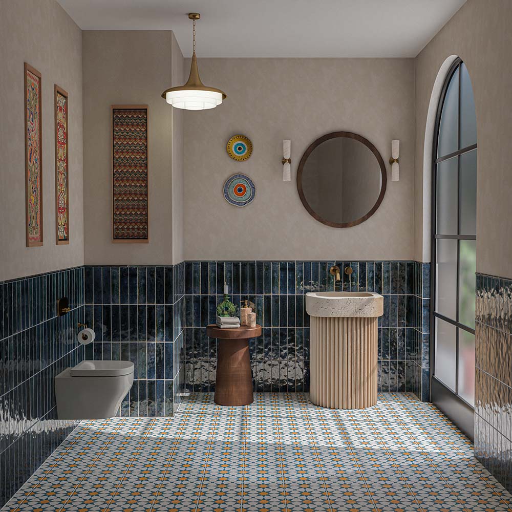 Contemporary bathroom featuring Izmir Blue 6x25cm glossy brick wall tiles, with deep navy blue tones and textured glaze variation, paired with colourful Moroccan-style patterned floor tiles, a fluted cream basin, brass fittings and neutral walls.