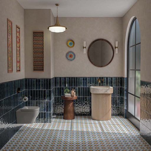 Contemporary bathroom featuring Izmir Blue 6x25cm glossy brick wall tiles, with deep navy blue tones and textured glaze variation, paired with colourful Moroccan-style patterned floor tiles, a fluted cream basin, brass fittings and neutral walls.
