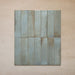 Group of Izmir Brick Celadon Green Gloss 6x25cm ceramic tiles displayed on a beige surface, showing subtle colour variation, glossy glaze, and handcrafted texture.