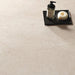 Close-up of Jeddah Avorio Neutra Stone 60x60cm stone-effect floor tiles, showcasing warm ivory and beige tones with delicate natural stone-inspired veining, styled with a black tray, soap dispenser and minimalist bathroom accessories.