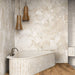 Bathroom featuring Jeddah Avorio Sassi Stone 30x60cm stone-effect wall and floor tiles, showcasing warm ivory and beige tones with natural stone-inspired detailing, paired with a freestanding fluted bath, timber flooring and wooden pendant lights.