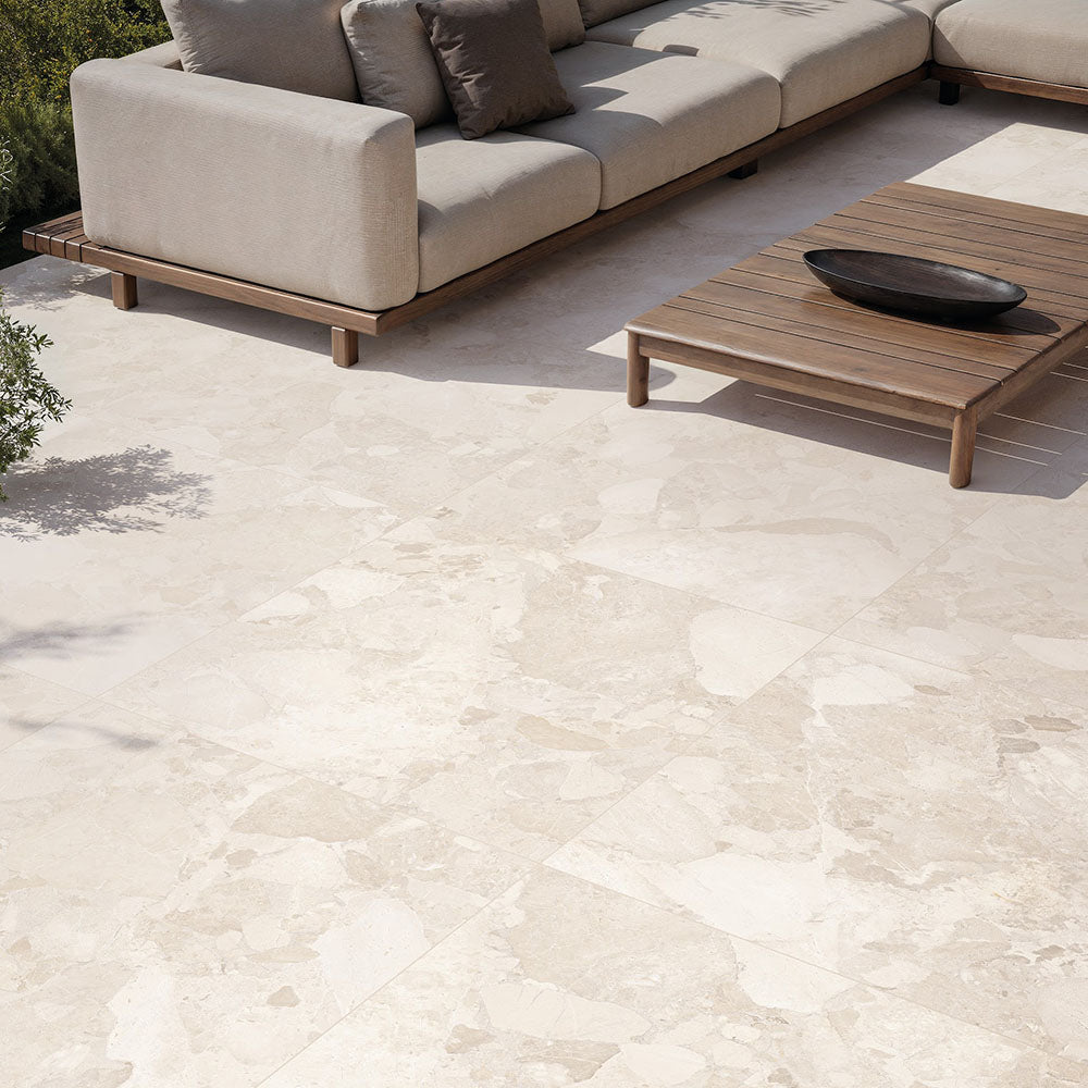 Contemporary outdoor patio featuring Jeddah Avorio Terrazzo 20mm 100x100cm outdoor stone-effect porcelain tile slabs, showcasing warm ivory and beige tones, paired with minimalist lounge seating, timber furniture and landscaped gardens.